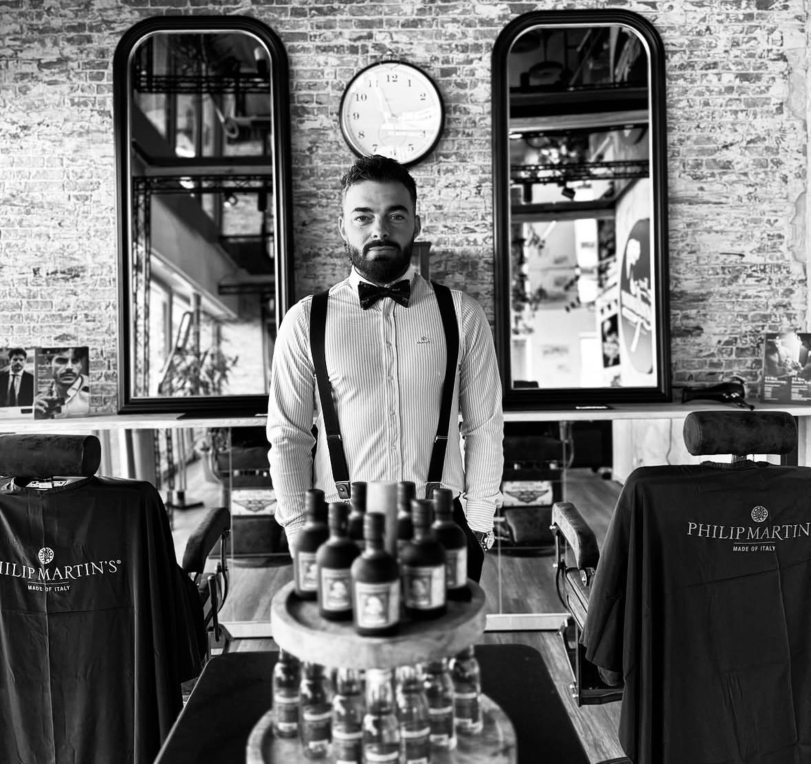 Barber v košili, motýlku a šlích v barbershopu True Gentleman